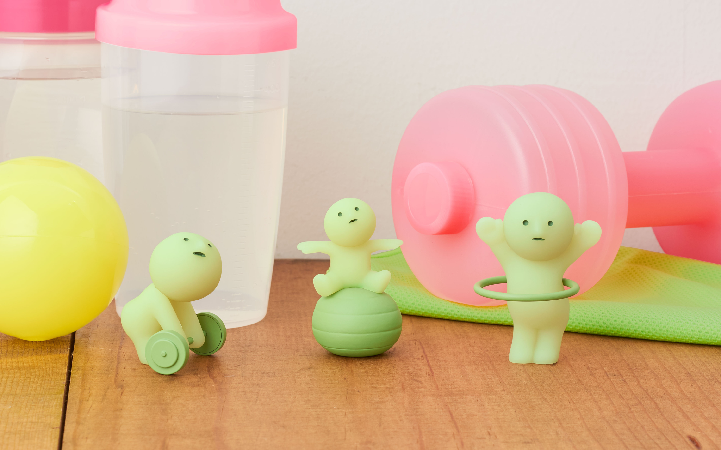 closeup of dumbell, yoga ball, and hoola hoop variants on a gym-themed background