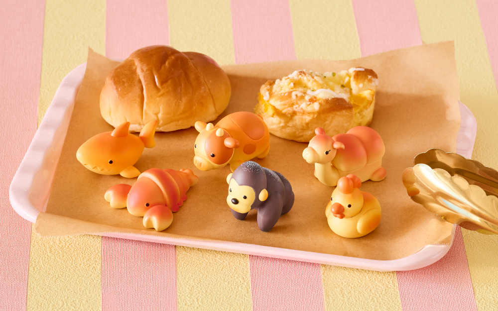 Wooden tray with bread-shaped animal figures on a striped pink and yellow background