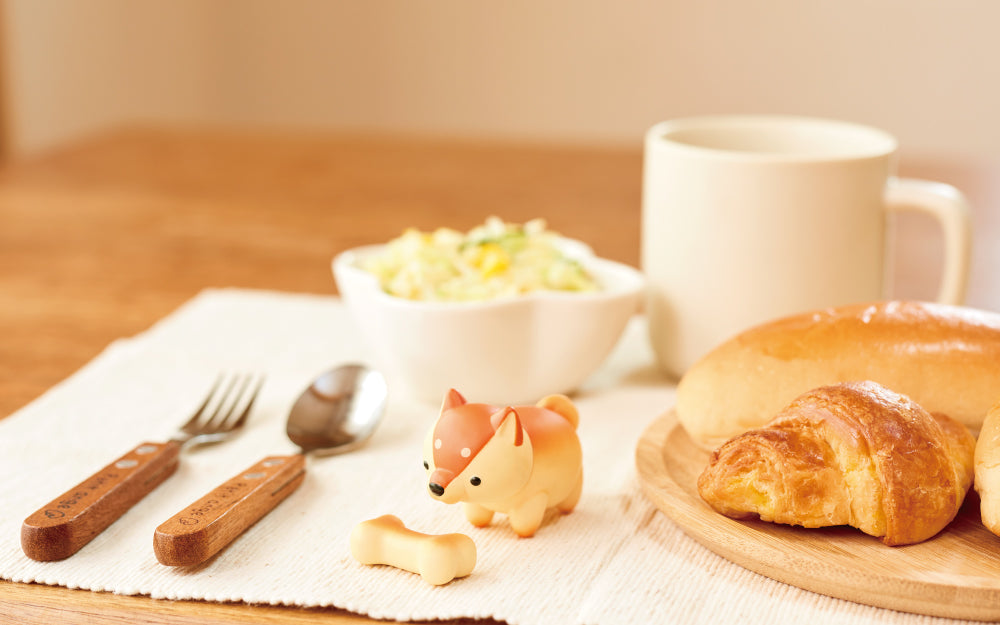 animal bakery shiba inu mini figure on a kitchen table with bone accessory and bread, silverware, placemat, and salad props