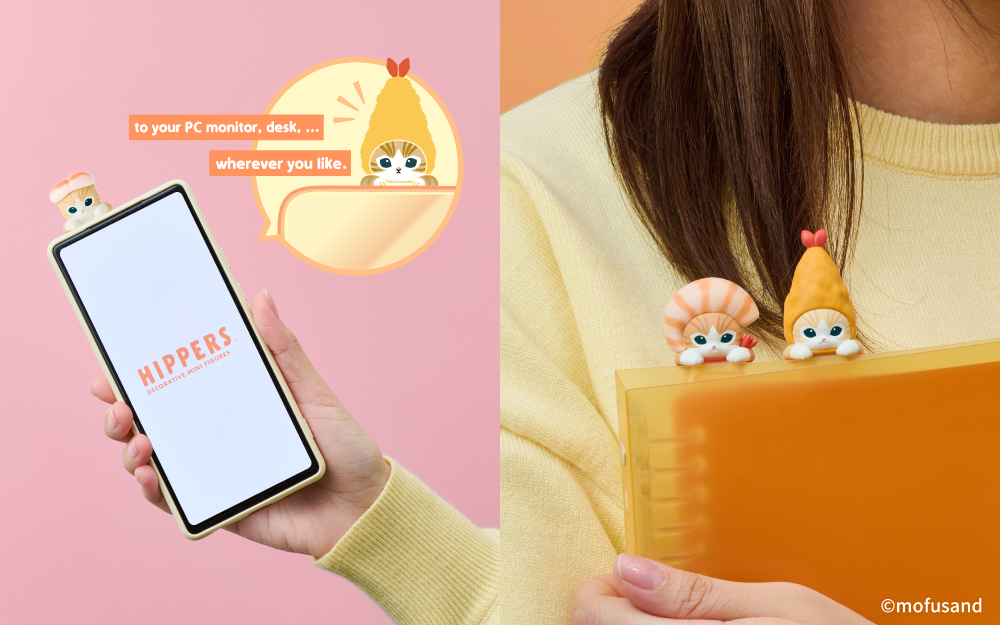 Split image shows new mofusand HIPPERS Shrimp Meow product. Left side image: set on a soft pink background, a hand holds a cell phone with the HIPPERS logo on the screen; Shrimp Sushi Meow HIPPER is on the top of the cellphone. Beside the cellphone, image includes a product logo with text "to your PC monitor, desk... wherever you like." beside a product image of Fried Shrimp Meow. Right side image: long haired person in yellow sweater holds an orange binder with Prawn Meow and Fried Shrimp Meow HIPPERS atop