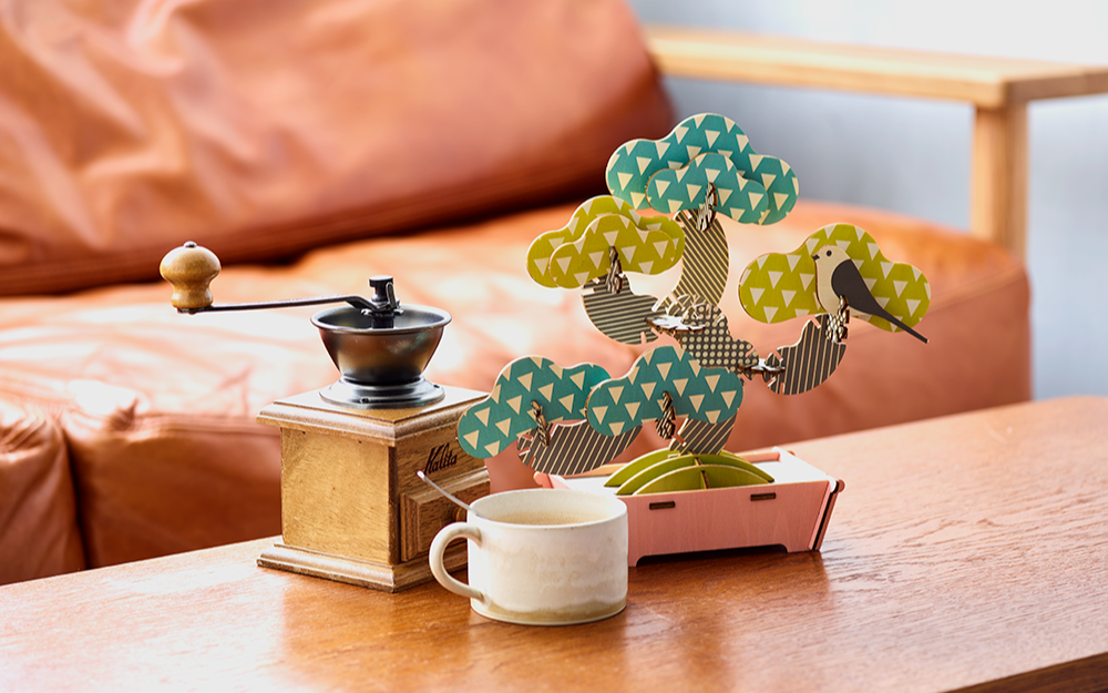 lifestyle image showing assembled bonsai puzzle on a table with coffee mug and coffee grinder props