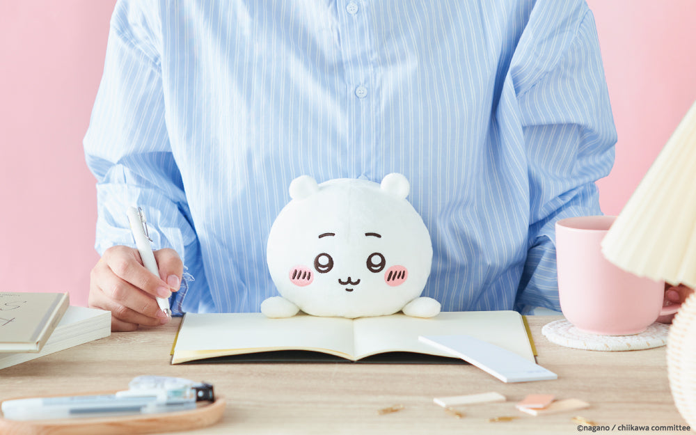 lifestyle image showcasing posture pal chiikawa. front facing view of a person in a blue striped shirt using posture pal chiikawa while they write in a notebook