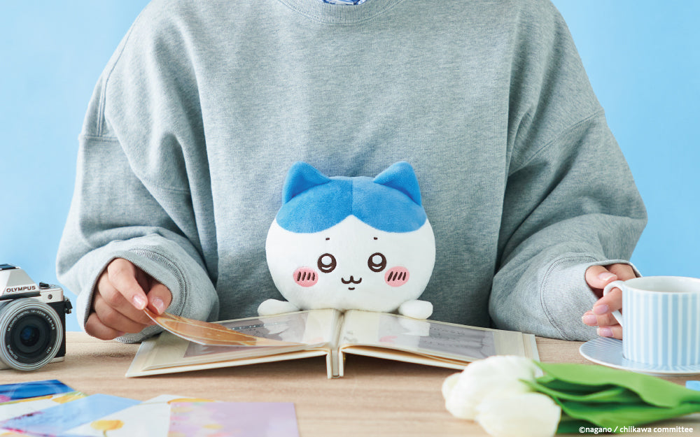 lifestyle image of posture pal chiikawa HACHIWARE edition. front facing view of person in a gray sweatshirt using posture pal hachiware while they are looking through a photo album