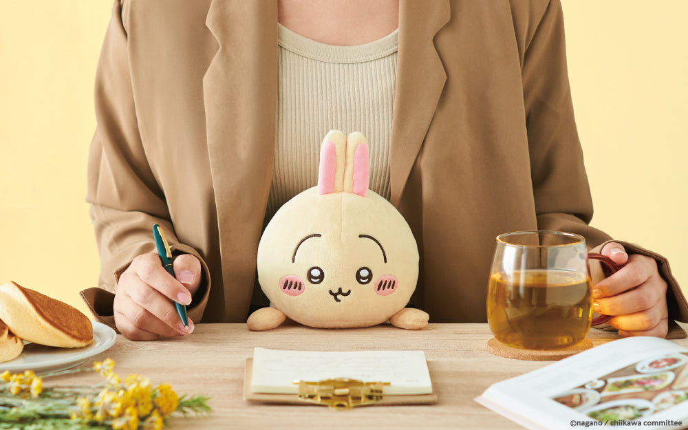 lifestyle image of posture pal chiikawa usagi edition. front facing view of a person in a brown blazer writing notes and using posture pal usagi to maintain posture