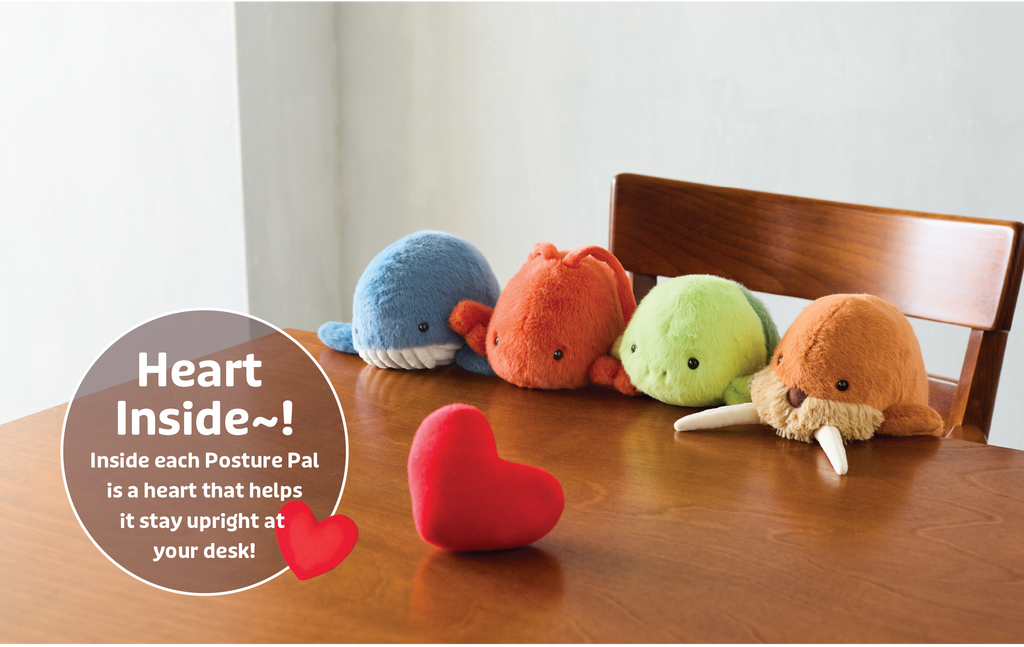 Image shows new lineup of Posture Pals- Marine. From left to right; blue whale, red/orange lobster, green turtle, brown walrus. Posture Pals sit on a wooden chair at a wooden table. A red heart also sits on the wooden table. Image include text: "Heart Inside~! Inside each Posture Pal is a heart that helps it stay upright at your desk!" text overlaid with a heart image. The images are set on a white background. 