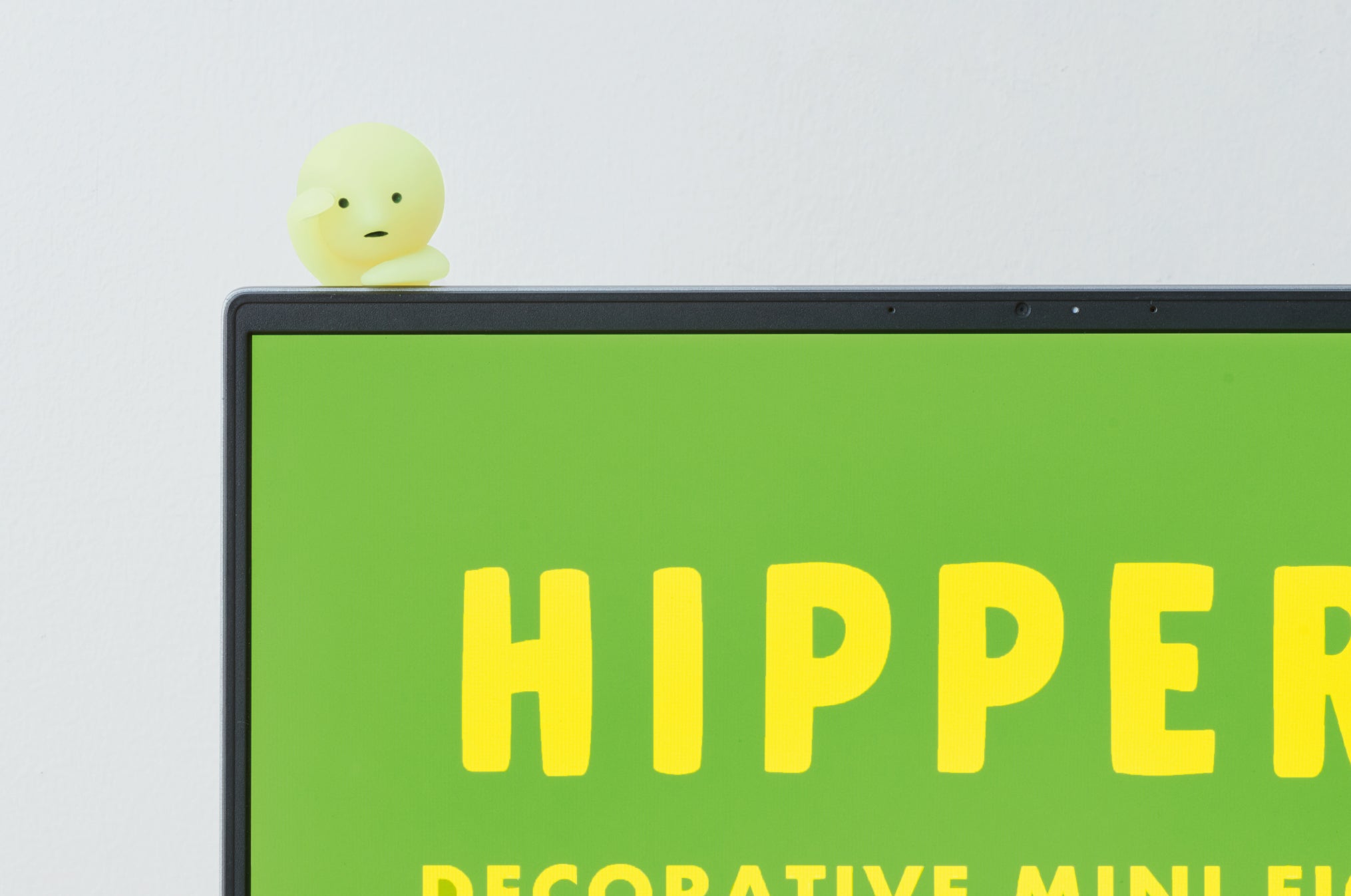 closeup lifestyle product image of the smiski LOOKING OUT hipper minifigure attached to a laptop