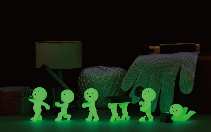 SMISKI Moving Series shows SMISKI minifigures glowing in the dark. From left to right minifigures include: SMISKI Carrying Ladder, SMISKI Balancing Boxes, SMISKI Decorating, SMISKI Teamwork, Green Thumb SMISKI and SMISKI Falling Down 