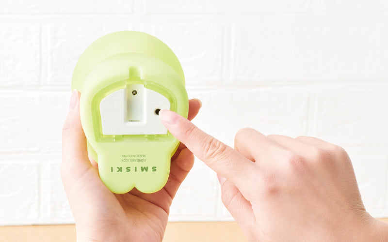 image of bottom of smiski touch light volume one showing the power port and a hand touching the power button
