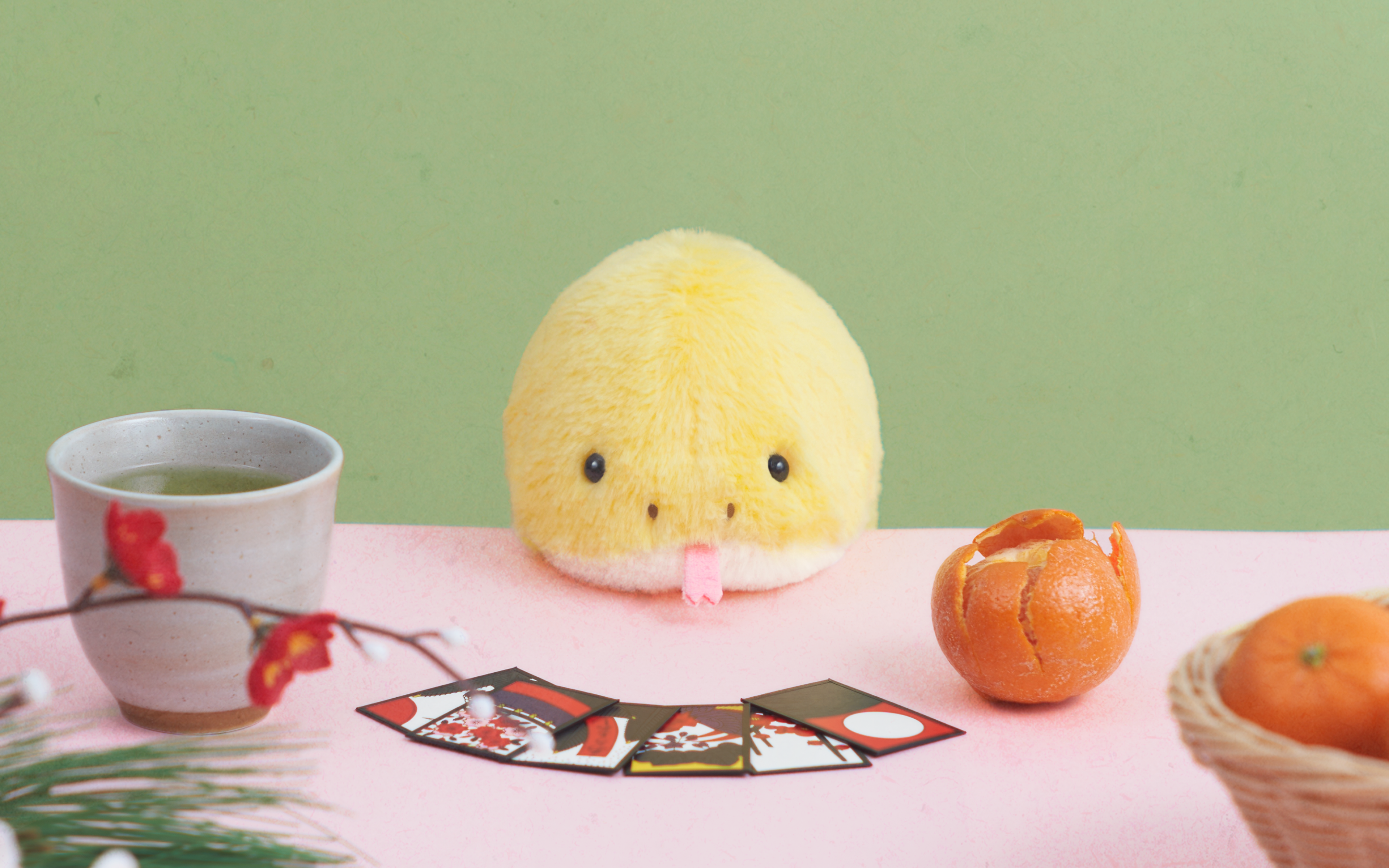 lifestyle image for posture pal snake yellow sitting at a desk with green tea, hanafuda cards, and oranges
