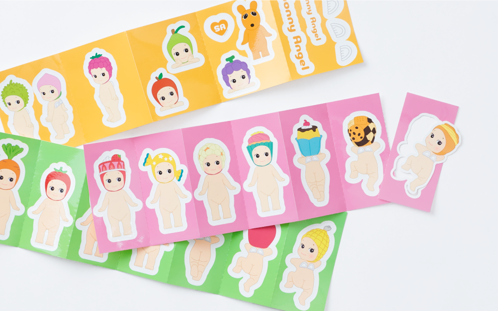 closeup of the sonny angel sticker pack series 2 die cut strips featuring stickers from the fruit, sweets, and vegetable series packs on a white backdrop