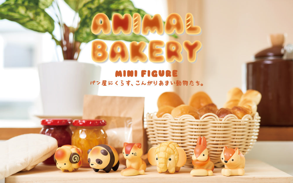 A display of adorable minifigures resembling baked goods, with a sign reading 'ANIMAL BAKERY MINIFIGURE'. The figures appear to be golden-brown in color, with details resembling animal faces and ears.