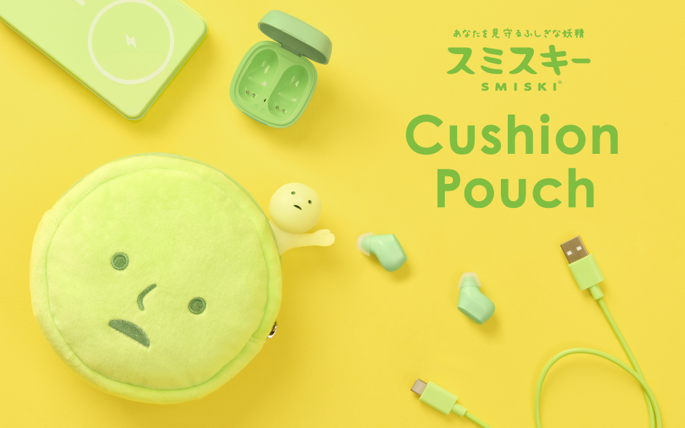 SMISKI in green text in both Japanese and English, above text "Cushion Pouch" set on yellow background. Light green charging brick, open green earpods case, green earpods, and green charging cable set around SMISKI Cushion Pouch with SMISKI figure tucked inside reaching outward. 
