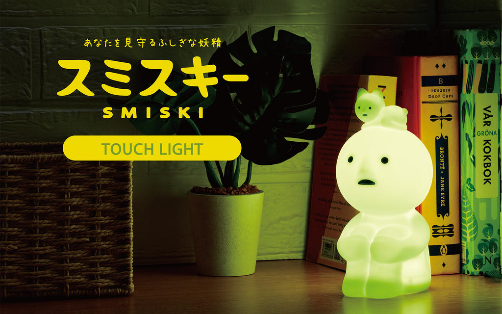 A promotional image featuring a 'Smiski Touch Light' with a depiction of a SMISKI glowing in a dimly lit room. The character is illuminated in a soft, green hue, and the text 'TOUCH LIGHT' is visible.