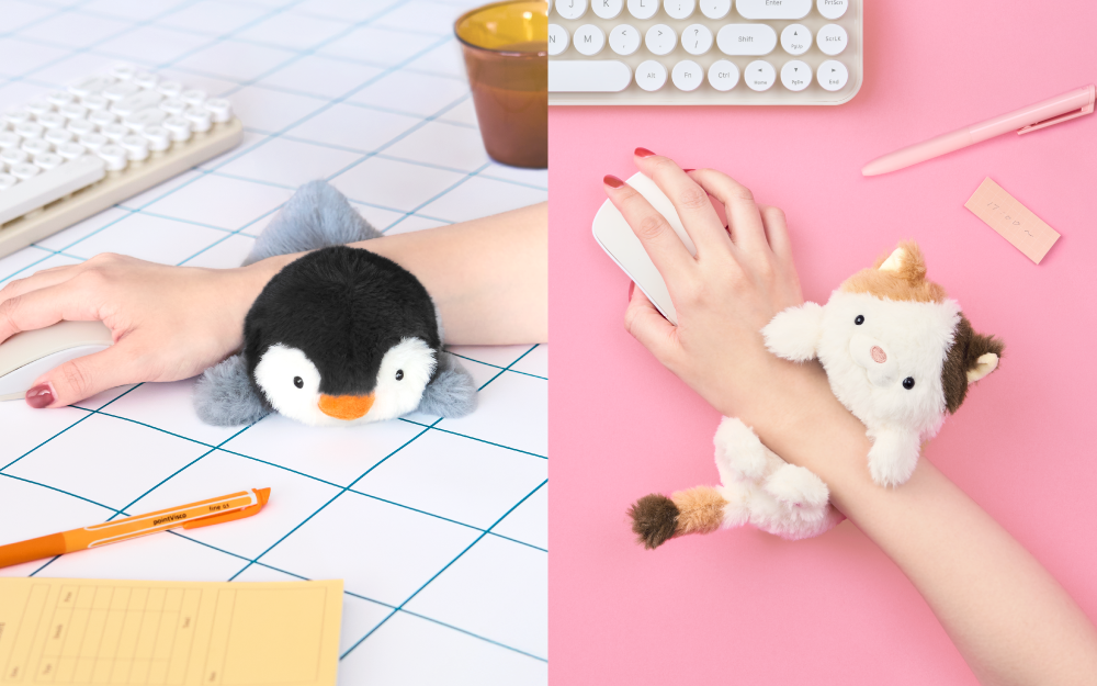 Split image shows new Posture Pal Wrist Cushion in two variants. Left: Arm and wrist rest on the penguin variant Wrist Cushion surrounded by work items. Right: Set against a pink background, a hand and arm sit atop the Calico Cat variant